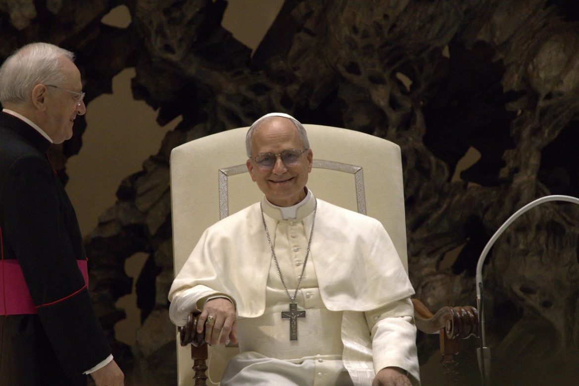 Pope Leo XIV smiling while seated in a white chair at the Vatican